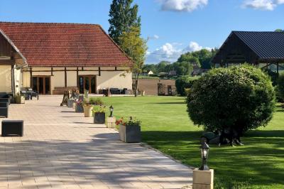 Lit double avec tête de lit sombre, draps gris et blancs, encadré par deux tables de chevet avec lampes, dans une chambre…