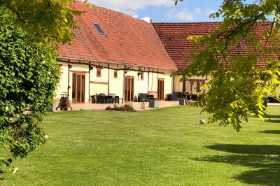 Lit double avec tête de lit sombre, draps gris et blancs, encadré par deux tables de chevet avec lampes, dans une chambre…