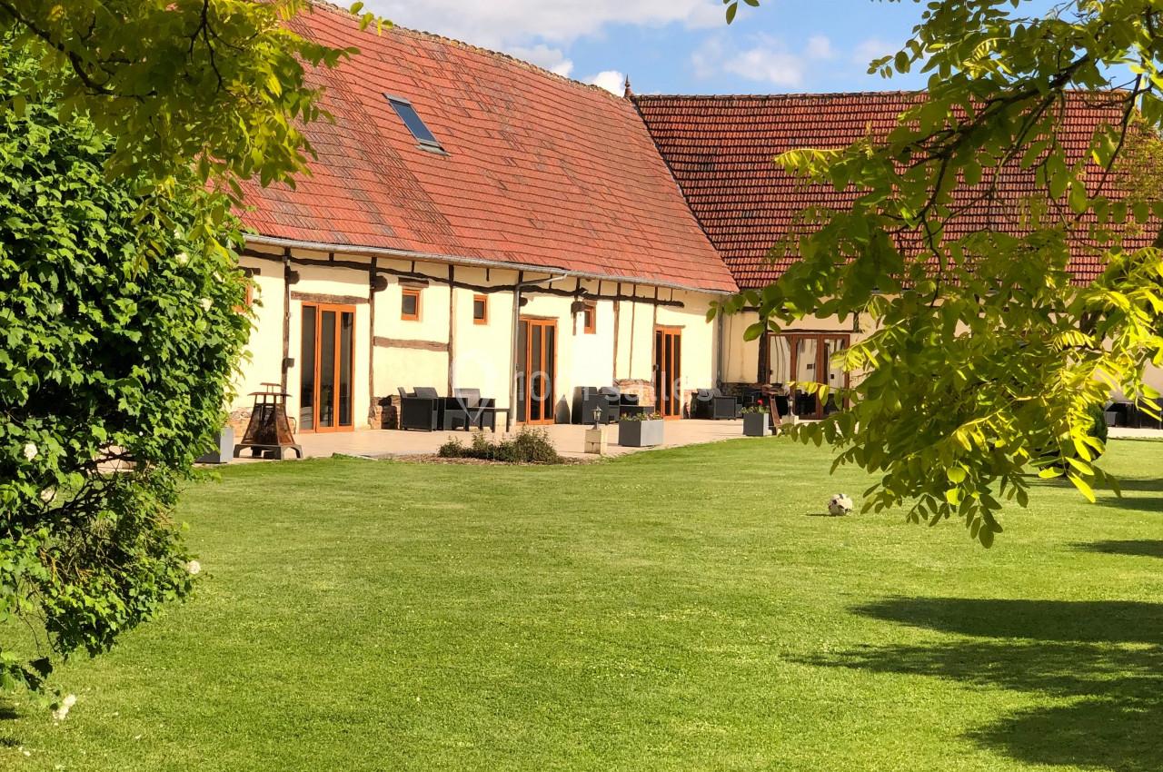 Bâtiment à toit rouge entouré de verdure avec une pelouse bien entretenue sous un ciel partiellement nuageux.