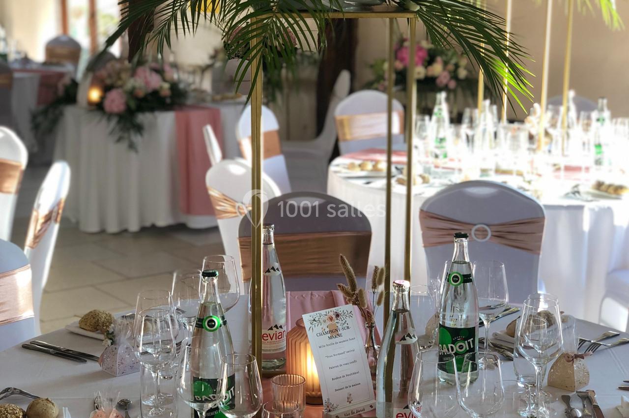 Table de réception élégamment dressée avec décoration florale, nappes blanches, chemins de table roses et vaisselle raffinée.
