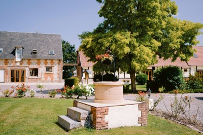 Table garnie de pâtisseries, macarons, fruits et biscuits, disposée en extérieur avec un jardin en arrière-plan.