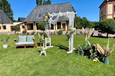 Table garnie de pâtisseries, macarons, fruits et biscuits, disposée en extérieur avec un jardin en arrière-plan.