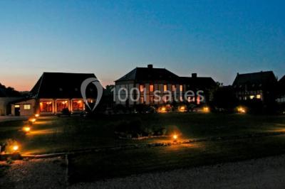 Lit double avec tête de lit sombre, draps gris et blancs, encadré par deux tables de chevet avec lampes, dans une chambre…