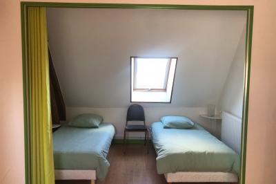 Lit double avec tête de lit sombre, draps gris et blancs, encadré par deux tables de chevet avec lampes, dans une chambre…