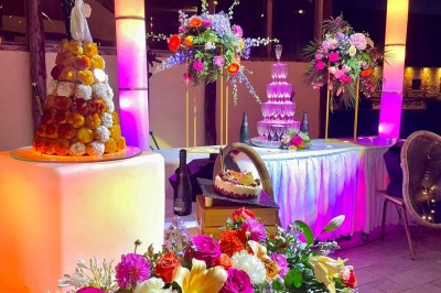 Table garnie de pâtisseries, macarons, fruits et biscuits, disposée en extérieur avec un jardin en arrière-plan.