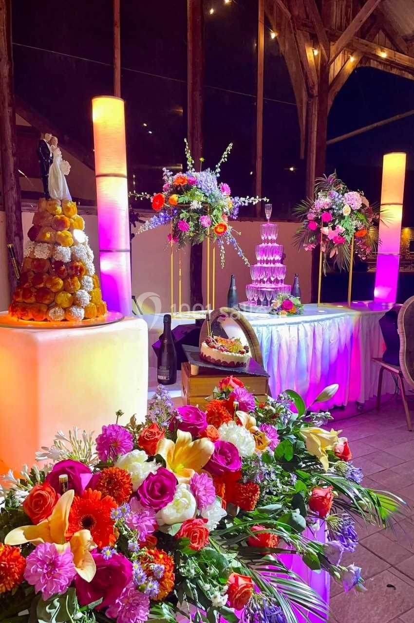 Table décorée pour une réception avec fleurs colorées, pièce montée, fontaine de champagne et éclairage chaleureux.