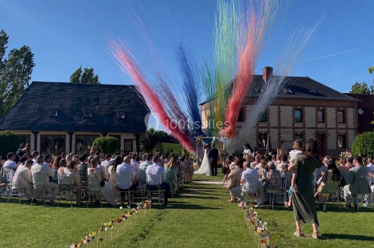 Cérémonie de mariage en plein air avec des invités assis et des jets de fumée colorée en arrière-plan.