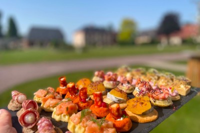 Table garnie de pâtisseries, macarons, fruits et biscuits, disposée en extérieur avec un jardin en arrière-plan.