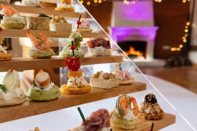Table garnie de pâtisseries, macarons, fruits et biscuits, disposée en extérieur avec un jardin en arrière-plan.