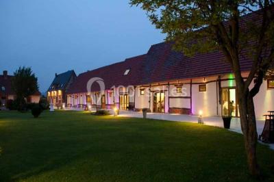 Lit double avec tête de lit sombre, draps gris et blancs, encadré par deux tables de chevet avec lampes, dans une chambre…