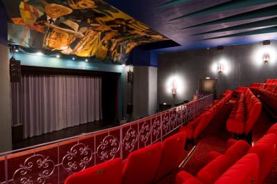 Piscine intérieure avec carrelage bleu, transats colorés et grandes baies vitrées laissant entrer la lumière naturelle.