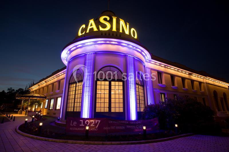 Façade illuminée d'un casino avec enseigne lumineuse ’Casino’, vue de nuit, entourée d'un chemin pavé et d'éclairages.