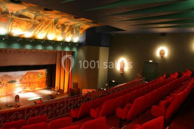 Piscine intérieure avec carrelage bleu, transats colorés et grandes baies vitrées laissant entrer la lumière naturelle.
