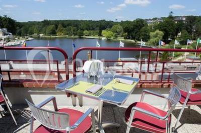 Piscine intérieure avec carrelage bleu, transats colorés et grandes baies vitrées laissant entrer la lumière naturelle.
