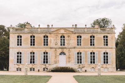 Groupe de personnes rassemblées dans un jardin près d'une bâtisse ancienne, sous une tente blanche par temps clair.