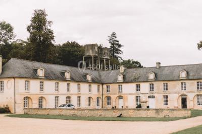 Groupe de personnes rassemblées dans un jardin près d'une bâtisse ancienne, sous une tente blanche par temps clair.