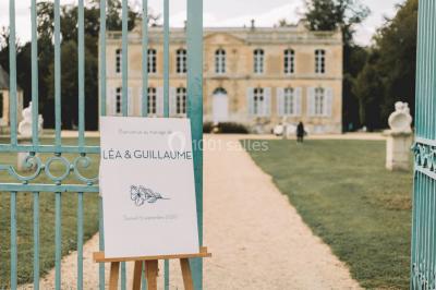 Groupe de personnes rassemblées dans un jardin près d'une bâtisse ancienne, sous une tente blanche par temps clair.