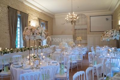 Groupe de personnes rassemblées dans un jardin près d'une bâtisse ancienne, sous une tente blanche par temps clair.