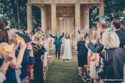 Groupe de personnes rassemblées dans un jardin près d'une bâtisse ancienne, sous une tente blanche par temps clair.