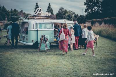 Groupe de personnes rassemblées dans un jardin près d'une bâtisse ancienne, sous une tente blanche par temps clair.