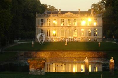Groupe de personnes rassemblées dans un jardin près d'une bâtisse ancienne, sous une tente blanche par temps clair.