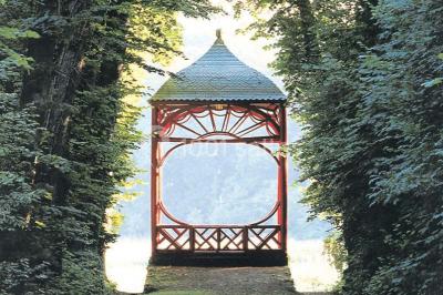Groupe de personnes rassemblées dans un jardin près d'une bâtisse ancienne, sous une tente blanche par temps clair.