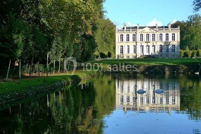 Groupe de personnes rassemblées dans un jardin près d'une bâtisse ancienne, sous une tente blanche par temps clair.