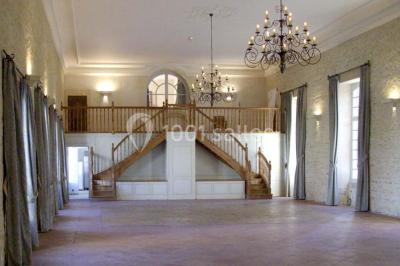 Groupe de personnes rassemblées dans un jardin près d'une bâtisse ancienne, sous une tente blanche par temps clair.