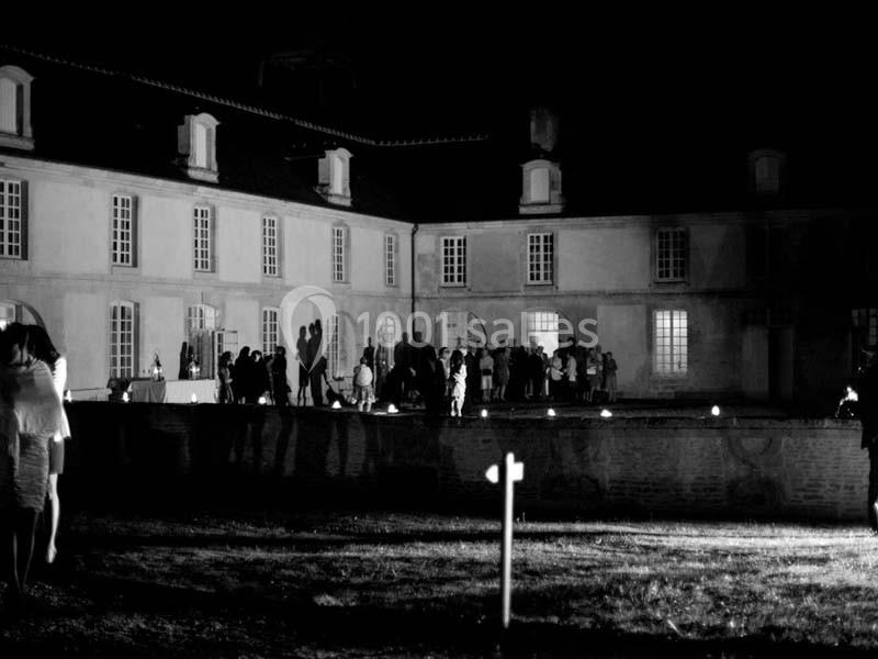 Groupe de personnes rassemblées devant un bâtiment éclairé la nuit, avec une ambiance festive.