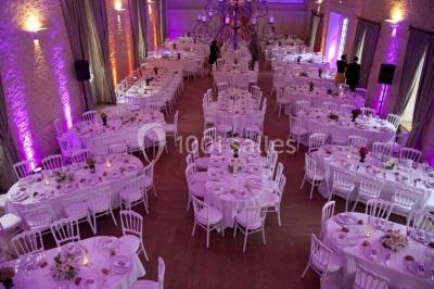 Groupe de personnes rassemblées dans un jardin près d'une bâtisse ancienne, sous une tente blanche par temps clair.