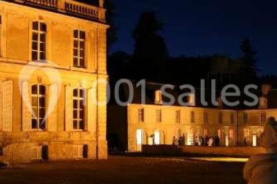 Groupe de personnes rassemblées dans un jardin près d'une bâtisse ancienne, sous une tente blanche par temps clair.