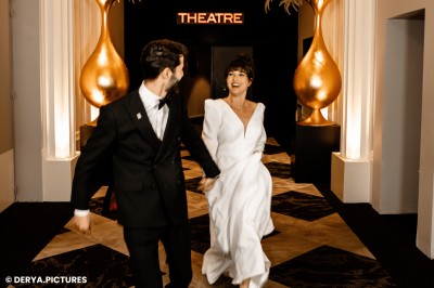 Un couple en tenue de mariage danse au milieu d'une salle de casino entourée de machines à sous.