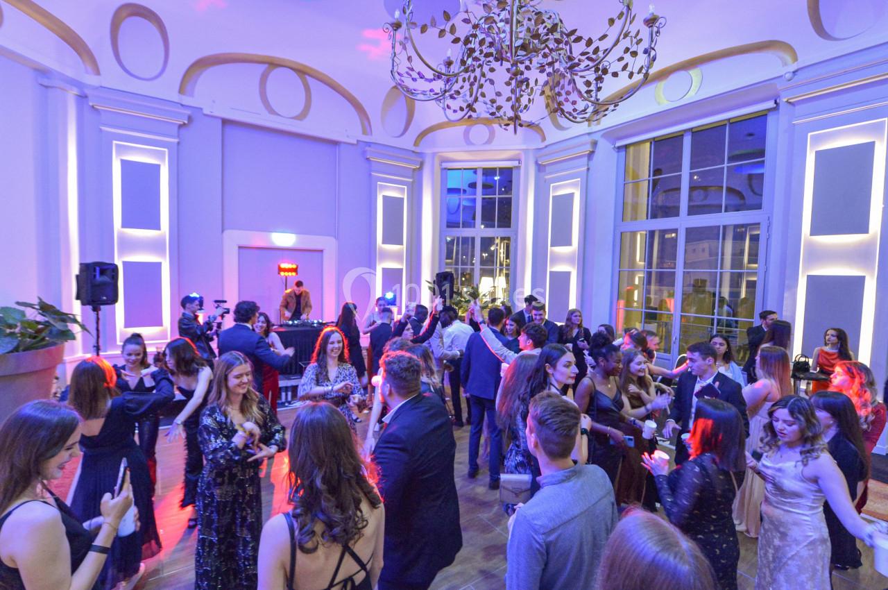 Personnes élégamment vêtues dans une salle lumineuse avec un lustre, participant à un événement festif.