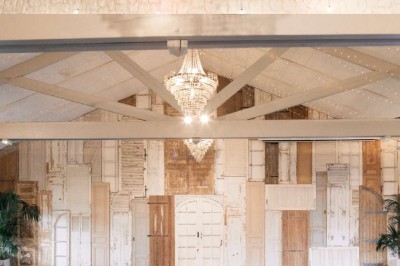 Vue d'une grange en bois entourée d'arbres, avec des bancs disposés en extérieur sur une pelouse.