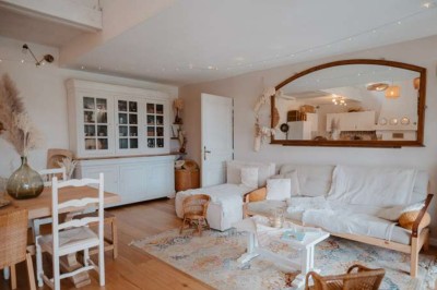 Vue d'une grange en bois entourée d'arbres, avec des bancs disposés en extérieur sur une pelouse.