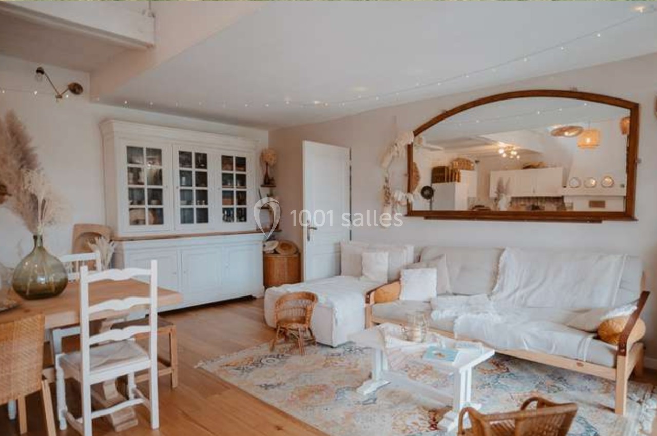 Salon lumineux avec canapé blanc, table basse, buffet vitré, grand miroir et décoration naturelle en bois et rotin.