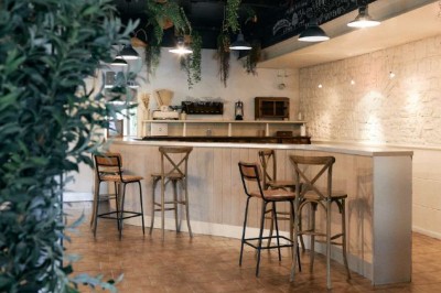 Vue d'une grange en bois entourée d'arbres, avec des bancs disposés en extérieur sur une pelouse.