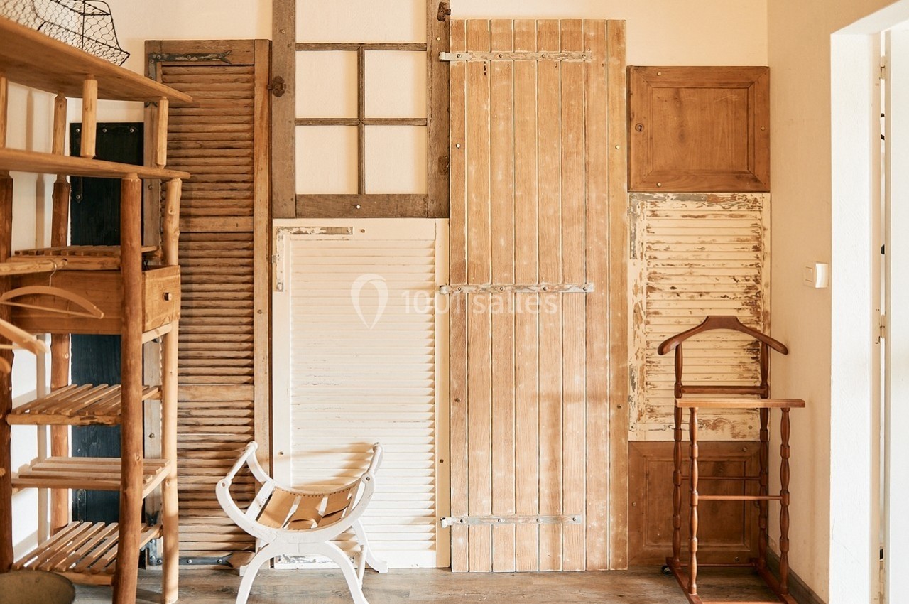 Ensemble de portes et volets en bois de styles variés, disposés contre un mur dans un intérieur lumineux.