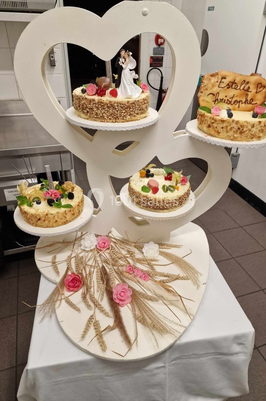 Présentoir en forme de cœur avec quatre gâteaux décorés de fruits et fleurs, accompagné d'épis de blé et roses.