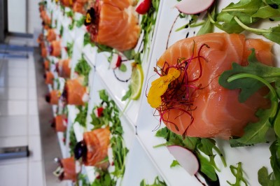 Choux noirs garnis de crème blanche et décorés de filet de caramel, disposés sur une surface métallique.