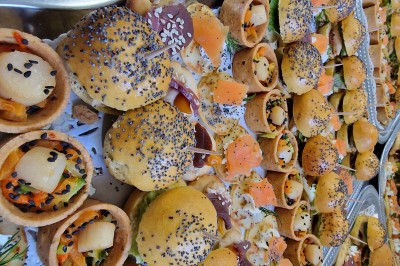 Choux noirs garnis de crème blanche et décorés de filet de caramel, disposés sur une surface métallique.