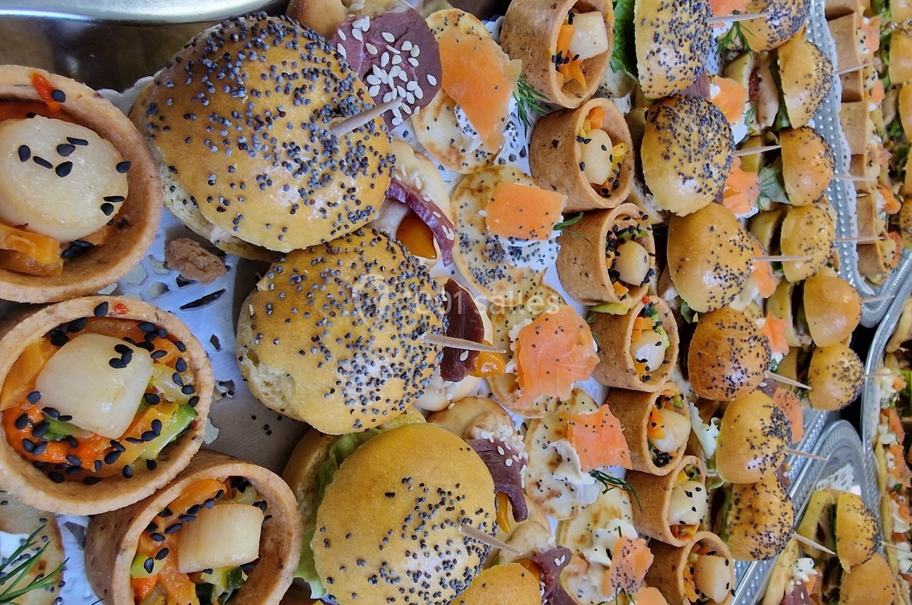 Plateau de bouchées apéritives variées, incluant mini-burgers, tartelettes aux légumes et canapés au saumon.