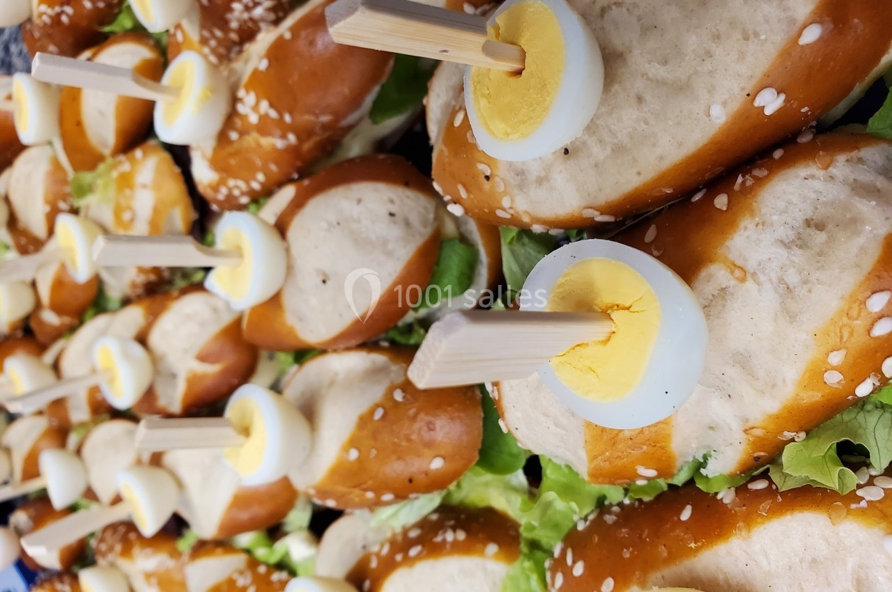 Mini-sandwichs au pain bretzel garnis de salade et surmontés de tranches d'œufs durs fixées avec des piques en bois.