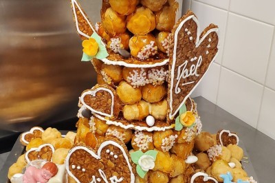 Choux noirs garnis de crème blanche et décorés de filet de caramel, disposés sur une surface métallique.