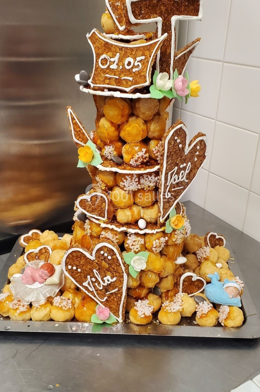Pièce montée en choux garnis, décorée de caramel, biscuits en forme de cœurs et motifs religieux.