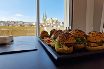 Choux noirs garnis de crème blanche et décorés de filet de caramel, disposés sur une surface métallique.