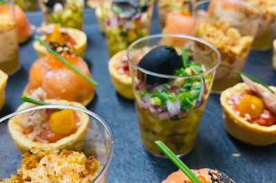 Choux noirs garnis de crème blanche et décorés de filet de caramel, disposés sur une surface métallique.