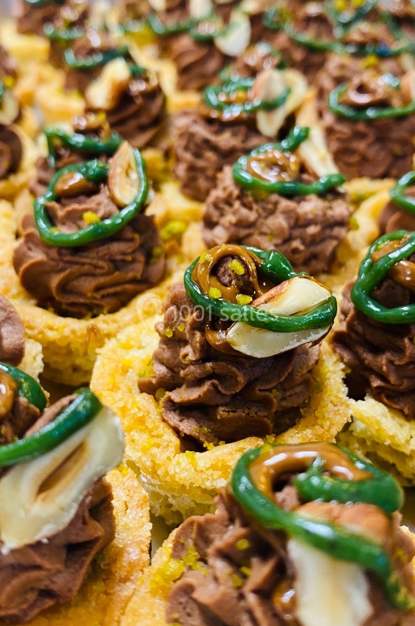 Petites bouchées garnies de mousse chocolatée, décorées de noisettes, caramel et filet de glaçage vert.