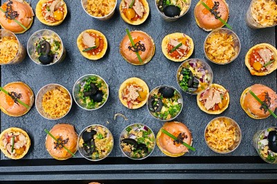 Choux noirs garnis de crème blanche et décorés de filet de caramel, disposés sur une surface métallique.