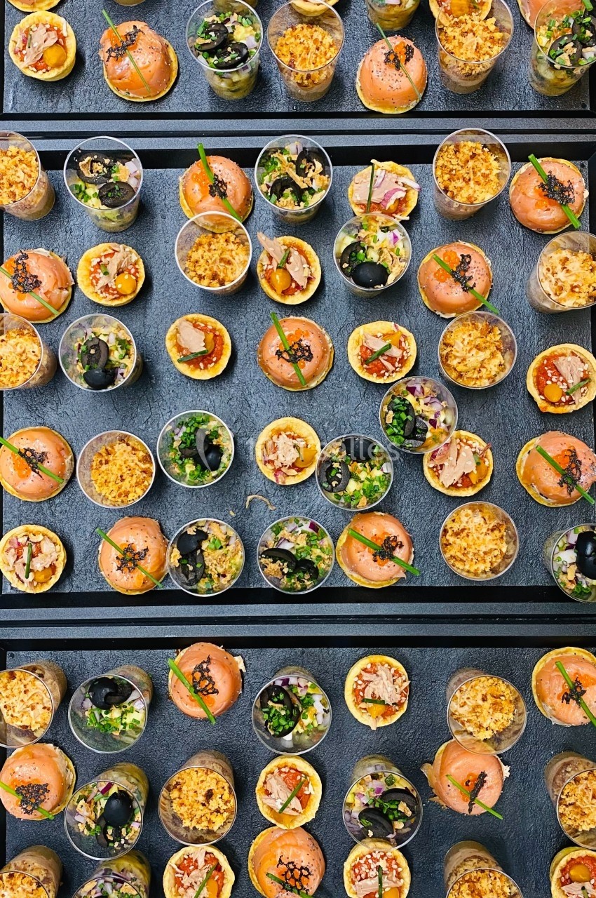 Assortiment de verrines colorées contenant des préparations variées, disposées sur une table sombre.